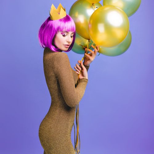 charming-beautiful-young-woman-attractive-fashionable-dress-with-flying-golden-balloons-pink-purple-haircut-crown-cheerful-emotions-closed-eyes-celebration_197531-1309