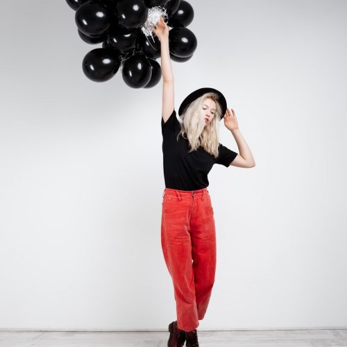 young-beautiful-blonde-girl-holding-black-baloons-white-wall_176420-11558
